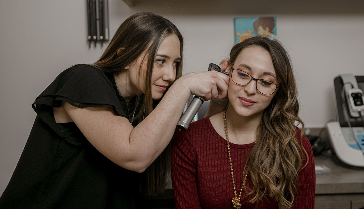 An Audiology student uses an instrument to look into a patient's ear