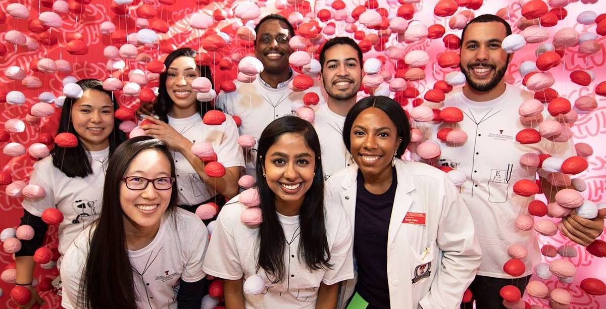 Eight students smiling and posing with brain backdrop
